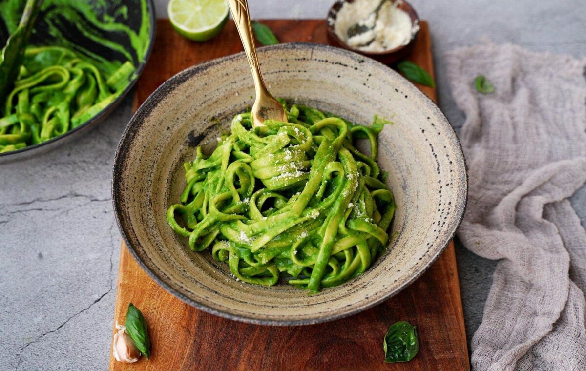 Horizontal shot of creamy spinach pasta in bowl with fork