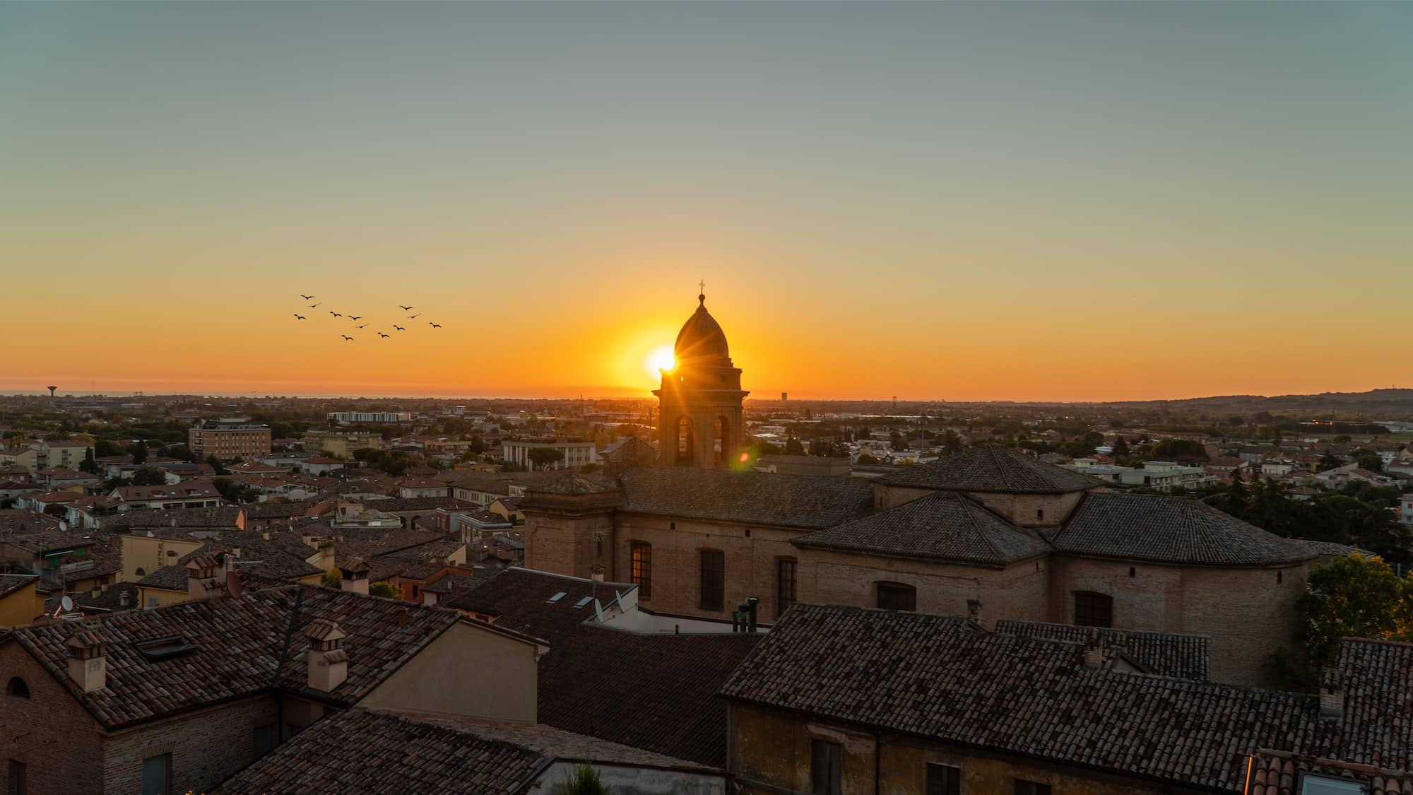 Sunrise in a city with old structures and birds